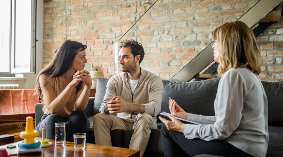 Terapia de casal. Casal conversando sobre o relacionamento e sendo acompanhados pela psicologa.